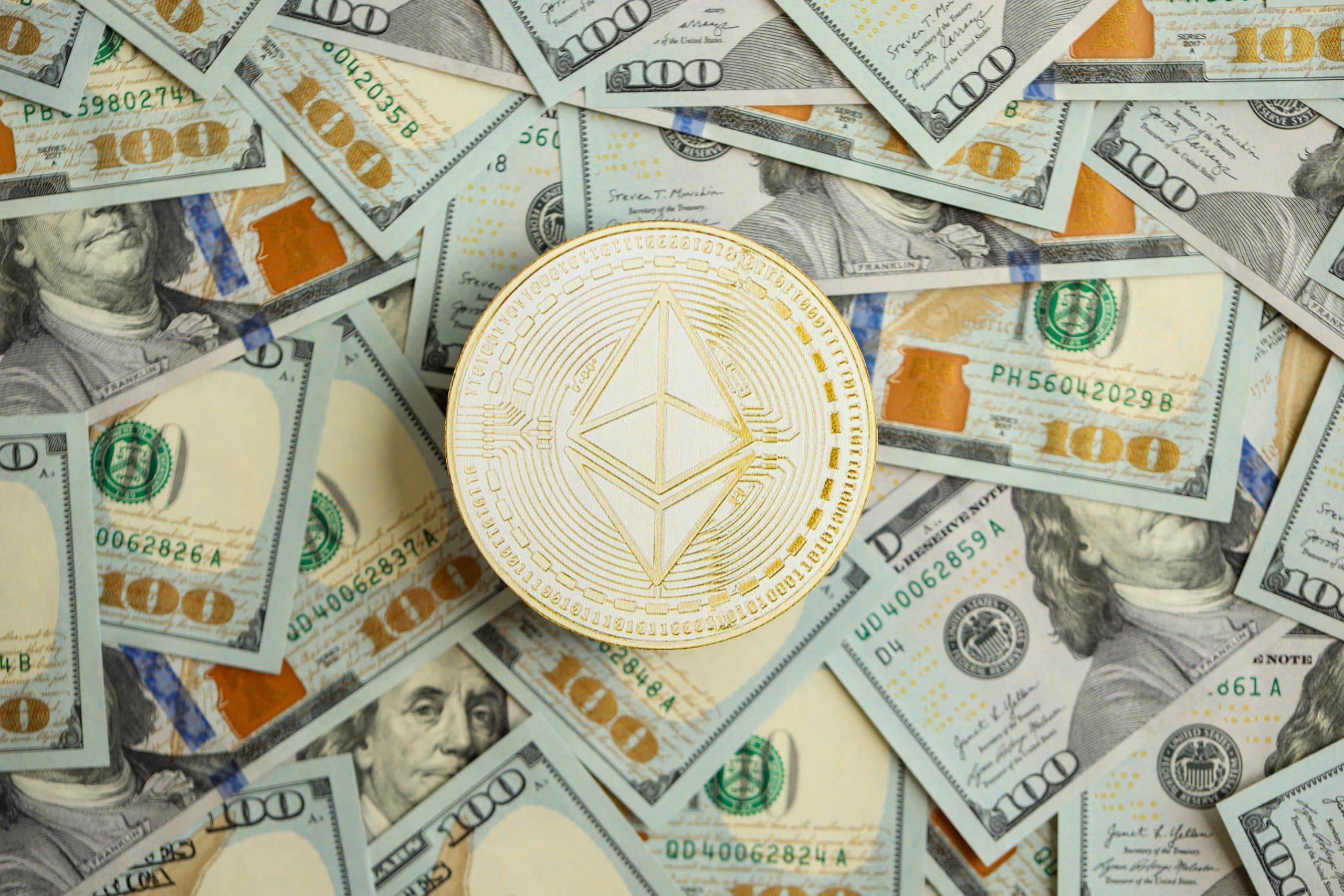 Eine Ethereum-Münze ruht auf einem verstreuten Stapel von 100-US-Dollar-Scheinen und symbolisiert die Verschmelzung von digitalen Vermögenswerten und traditioneller Währung.