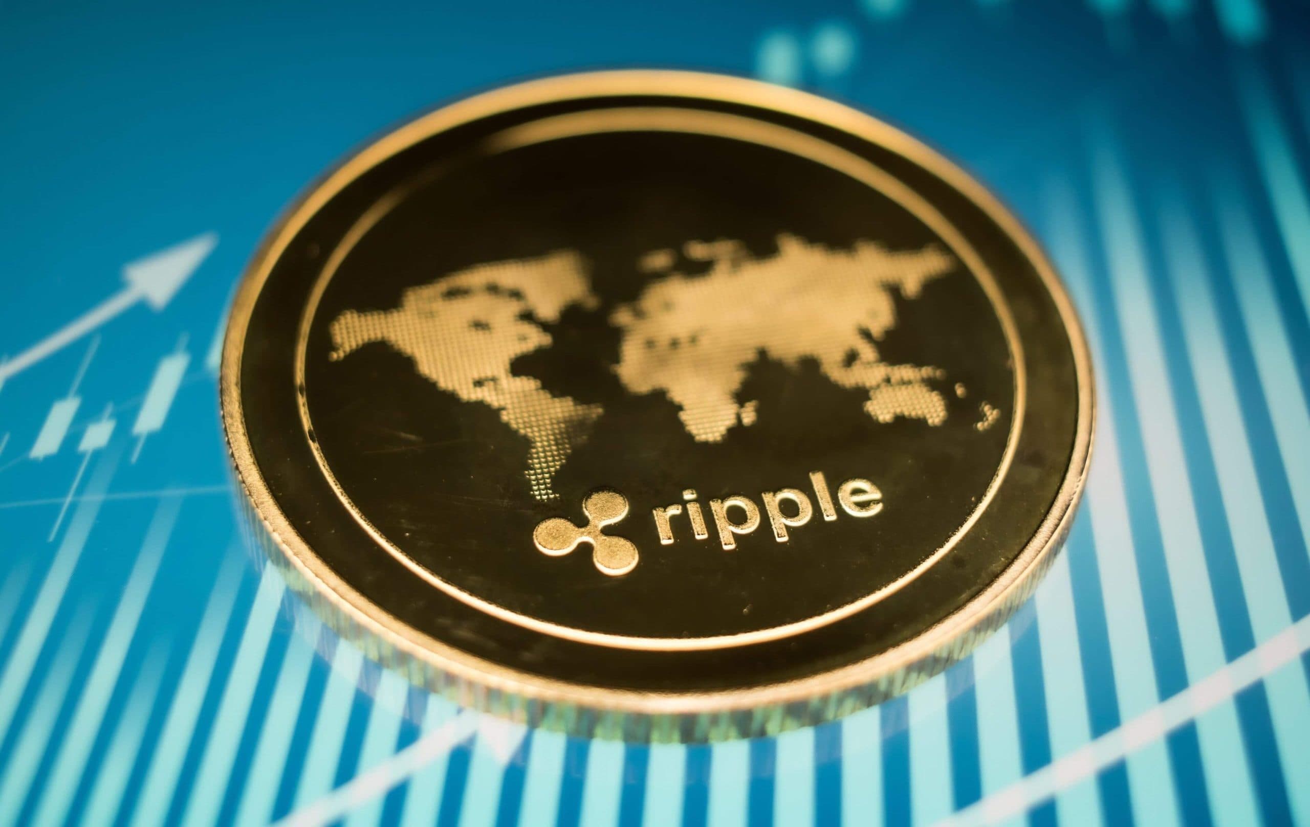 Eine Nahaufnahme einer goldenen Ripple (XRP)-Kryptowährungsmünze mit einem Weltkartenmotiv auf blauem Hintergrund mit Finanzdiagrammlinien.